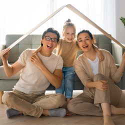 Mother, father and child girl in the room with a symbol of roof. Concept of housing for young family.